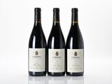 three bottles of red wine are lined up on a white surface