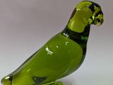 un oiseau en verre vert posé sur une surface blanche