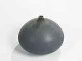 a small black vase sitting on a white surface