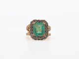a gold ring with an emerald stone surrounded by black diamonds