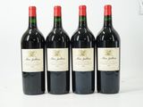 quatre bouteilles de vin rouge sont alignées sur une table