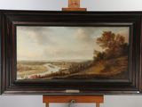 painting on easel of a landscape with a river and a village in the distance
