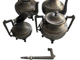 trois théières en argent et une théière posée sur un socle