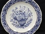 une assiette bleue et blanche sur laquelle est représenté un panier de fleurs