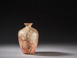 un vase en verre orange posé sur une surface blanche