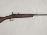 un fusil posé sur une surface blanche, avec une crosse en bois