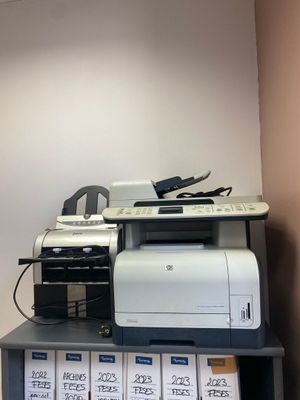 a printer sitting on top of a shelf in the corner of a room
