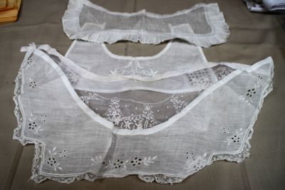 three pieces of white lace on a bed