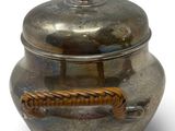 an old silver pot with a rope handle on a white surface
