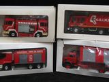 trois camions de pompiers rouges dans leurs boîtes, sur fond noir