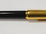 une image représentant un stylo noir et doré posé sur une surface blanche