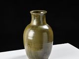 un grand vase vert posé sur une table blanche