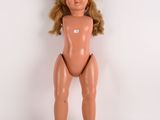 une image représentant une poupée nue aux cheveux blonds sur fond blanc