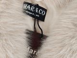 the label on a white fur coat is attached to a black and white tag