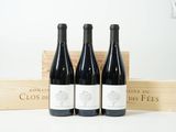 trois bouteilles de vin dans une caisse en bois, avec une autre caisse en bois derrière elles