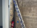 une échelle appuyée contre un mur, à côté d'une borne d'incendie
