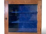 une petite armoire en bois avec une porte vitrée et des étagères
