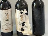 trois bouteilles de vin posées sur une table, à côté d'une feuille de papier