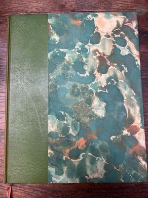 un livre vert ouvert posé sur une table en bois, à côté d'une paire de ciseaux