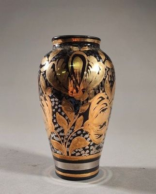 un vase noir et or posé sur une surface blanche