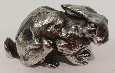 une figurine de lapin en argent posée sur une surface blanche