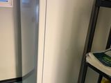 un réfrigérateur blanc dans une petite pièce avec une fenêtre