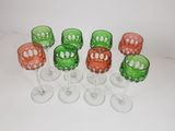 six verres à vin verts et rouges posés les uns à côté des autres sur une surface blanche