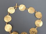 un bracelet en or orné d'un motif représentant une pièce de monnaie