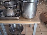 Plusieurs casseroles et poêles sont posées sur une table dans une cuisine.