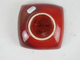 a red vase with a tag on it on a table