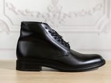 un gros plan sur une paire de bottes en cuir noir posées sur une table en bois
