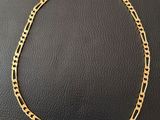un collier à chaîne en or posé sur une surface noire