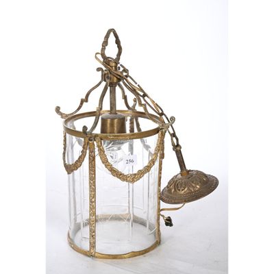 une lanterne ancienne en laiton et en verre, ornée d'une clochette, sur fond blanc