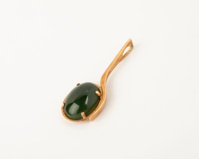 a close up of a green stone on a gold plated spoon