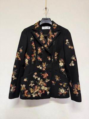 une veste noire ornée de fleurs, suspendue à un cintre