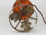 a small orange glass object with a leaf decoration on it