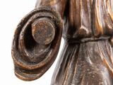 a wooden statue of a woman holding a hat