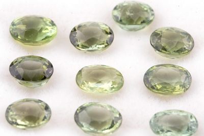 Les pierres précieuses vertes sont disposées en cercle sur une surface blanche.