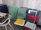une pièce où se trouvent de nombreuses chaises de différentes couleurs et une table