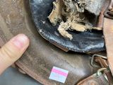 a hand pointing at a worn helmet on the floor