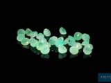 a close up of a bunch of green stones on a black surface