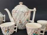 four cups and a teapot sitting on a table