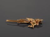 a gold bird brooch on a black surface