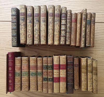 several old books are lined up on a shelf on a wooden table