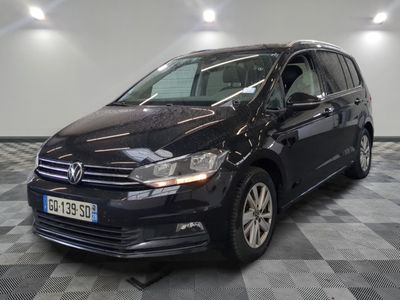 La Volkswagen Touran est garée dans une grande pièce au sol carrelé en damier.