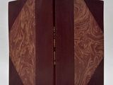 the book is open on a white surface with a brown cover