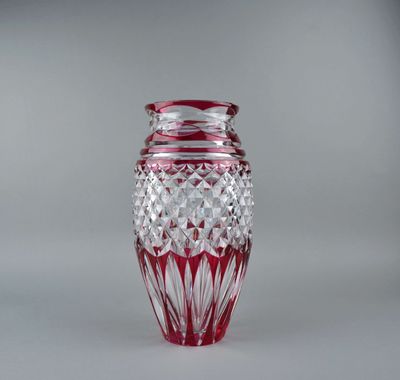 a glass vase with a red base on a white surface