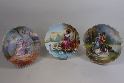 trois assiettes décoratives représentant des personnes, posées sur une table