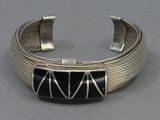 a close up of a silver bracelet with a black stone in the center
