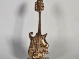 figurine de guitare en laiton posée sur un socle en marbre, sur fond blanc